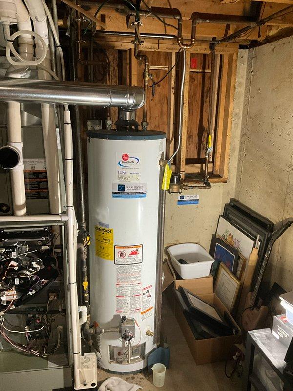 Completed comprehensive plumbing inspection of lower level bathroom and mechanical room. Inspected dual showerhead system with rain head and handheld unit, verified proper operation of brushed nickel fixtures and faucet controls, and confirmed white subway tile surround in good condition with no visible leaks or water damage. Examined water heater, associated copper and PEX supply lines, drainage system, and overhead plumbing connections in utility area, documenting all components with photos for maintenance records.