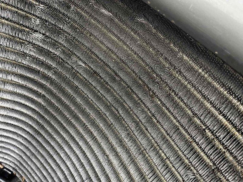 Completed comprehensive BFMA preventive maintenance tune-up on residential air conditioning system. Performed thorough inspection of outdoor condenser unit, noting moderate dust and debris accumulation on finned heat exchanger coil requiring cleaning. Cleaned condenser coils to restore optimal airflow and heat transfer efficiency, removing dirt, grime, and environmental debris lodged between aluminum fins. Verified proper operation of condenser fan motor and compressor, inspected refrigerant lines and electrical connections, and confirmed unit mounted securely on concrete pad. System operating within normal parameters upon completion of maintenance service.