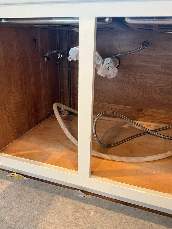 Successfully reconnected kitchen sink, dishwasher, and garbage disposal plumbing connections under cabinet. Installed and secured water supply lines and drain hoses for all fixtures, ensuring proper fit and leak-free operation of the undermount stainless steel sink with modern single-lever faucet assembly.