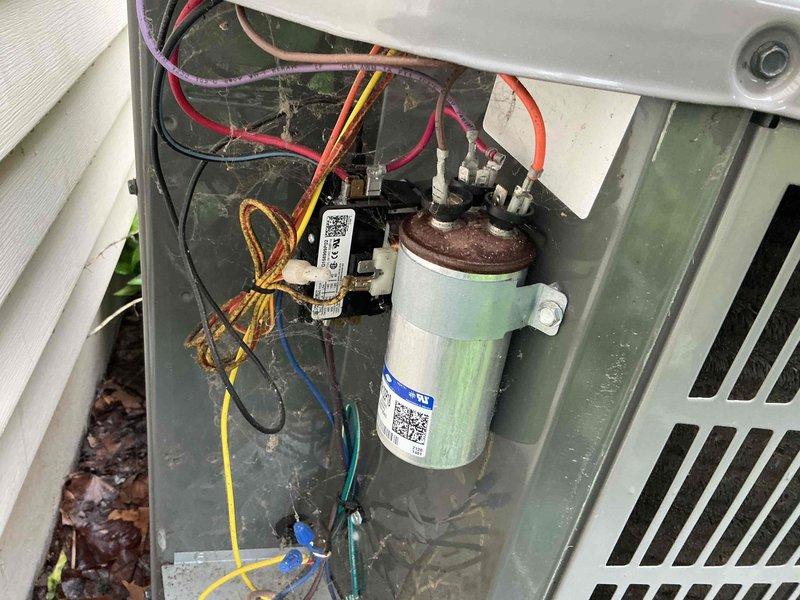 Responded to no cooling call at residential property. Upon inspection, found failed capacitor in outdoor condensing unit with visible corrosion on terminals and mounting bracket. Verified equipment warranty status showing 10-year parts coverage active through 2031 on both furnace and air conditioning systems. Replaced defective capacitor, tested system operation, and restored cooling functionality to unit.