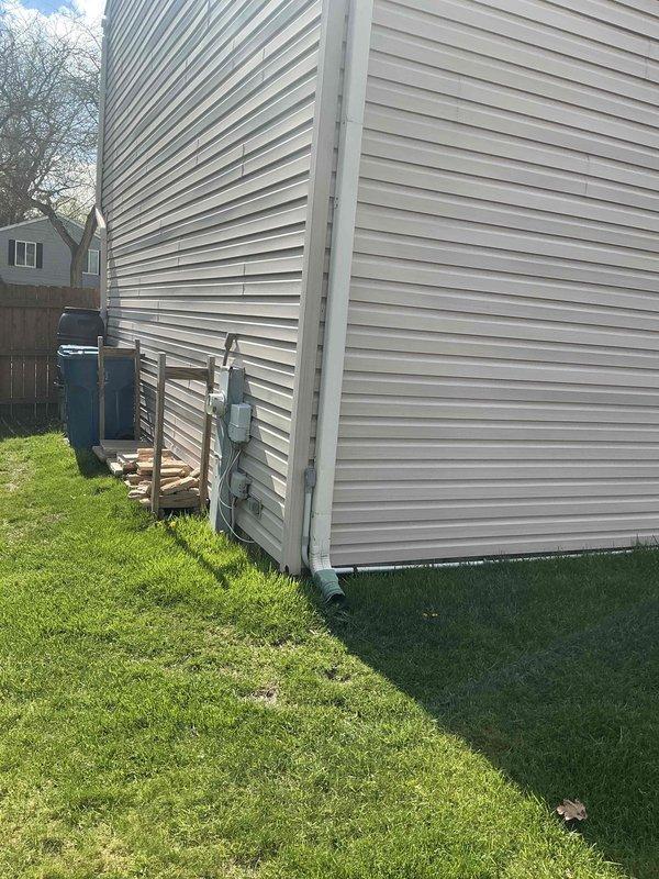 Provided comprehensive estimate for complete air conditioning system replacement including new outdoor condensing unit and indoor evaporator coil. Assessment included evaluation of existing equipment placement and feasibility of relocating outdoor condenser unit to more optimal position on exterior of residence. Documented current HVAC configuration in basement mechanical room with furnace, ductwork connections, and existing refrigerant lines, as well as current condenser location adjacent to building exterior wall to determine scope of work required for system upgrade and equipment relocation.