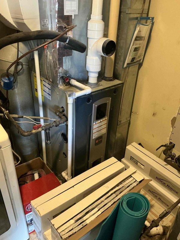 Provided comprehensive estimate for complete air conditioning system replacement including new outdoor condensing unit and indoor evaporator coil. Assessment included evaluation of existing equipment placement and feasibility of relocating outdoor condenser unit to more optimal position on exterior of residence. Documented current HVAC configuration in basement mechanical room with furnace, ductwork connections, and existing refrigerant lines, as well as current condenser location adjacent to building exterior wall to determine scope of work required for system upgrade and equipment relocation.