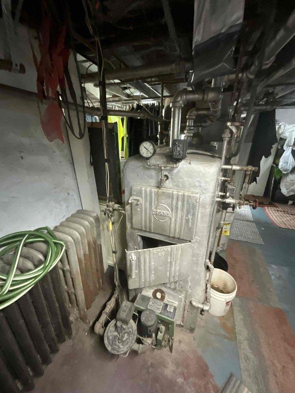 Conducted on-site assessment of existing boiler system for replacement estimate. Evaluated aged heating unit with low water cut-off control, noting significant deterioration, rust accumulation, and outdated components throughout the system. Documented current equipment configuration including piping layout, electrical connections, and basement installation conditions to provide comprehensive replacement proposal based on reference installation specifications.