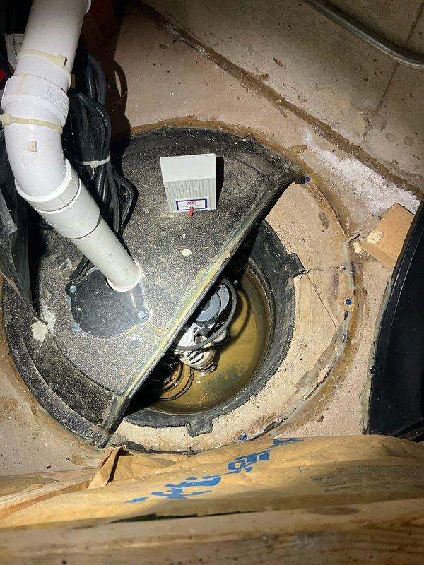 Responded to residential service call for drainage issues and sump pump assessment. Conducted thorough inspection of existing sump pump system, including examination of wall-mounted access panel containing plumbing infrastructure and evaluation of sump basin with yellow pump mechanism, discharge piping, and electrical connections. Documented current system condition and provided comprehensive estimate for sump pump solutions to address ongoing drainage concerns.
