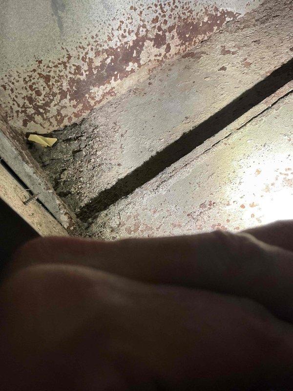 Responded to after hours call for HVAC system issue. Upon arrival, found thermostat displaying 61°F and investigated equipment area revealing significant moisture damage and deterioration at concrete junction near mechanical components. Observed extensive rust staining, water damage along seams, and possible mold growth indicating ongoing moisture intrusion affecting system operation. Documented conditions with photos for follow-up assessment and remediation recommendations.