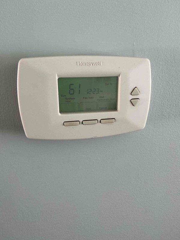Responded to after hours call for HVAC system issue. Upon arrival, found thermostat displaying 61°F and investigated equipment area revealing significant moisture damage and deterioration at concrete junction near mechanical components. Observed extensive rust staining, water damage along seams, and possible mold growth indicating ongoing moisture intrusion affecting system operation. Documented conditions with photos for follow-up assessment and remediation recommendations.