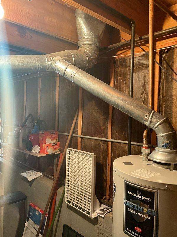 Conducted comprehensive in-home assessment for full HVAC system replacement in residential basement location. Evaluated existing dark gray furnace unit with lower front ventilation grille, extensive silver metal ductwork system with both vertical and horizontal runs, and cream-colored cylindrical humidifier canister mounted to ductwork with dual circular ports. Inspected Bradford White Defender water heater with safety system located in utility area. Assessed basement infrastructure including exposed concrete block foundation walls, wooden framing studs, black electrical wiring, and copper plumbing/gas lines. Documented complete mechanical room layout with concrete slab flooring and current equipment configuration. Gathered specifications and measurements necessary to propose appropriate replacement equipment sized for individual home comfort requirements. Prepared detailed estimate for full system upgrade including furnace, ductwork modifications, and humidification components.