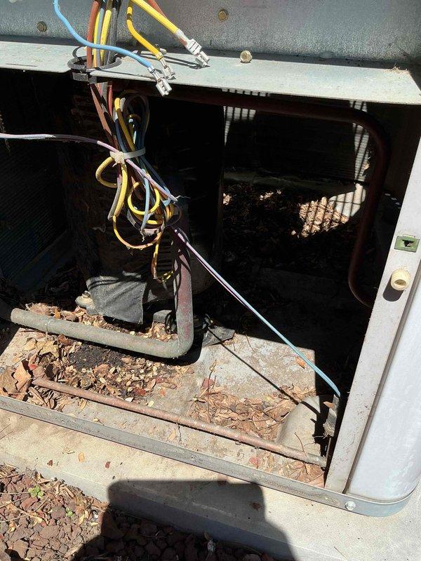 Completed comprehensive BFMA tune-up on 23-year-old air conditioning system. Removed access panel and cleared significant debris accumulation including dried leaves and dirt from unit base and interior components. Inspected condenser coil, electrical connections, and wiring harnesses; verified all terminal blocks secure and properly connected. Replaced dual-run capacitor with new component to ensure optimal compressor and fan motor operation. Cleaned exterior housing, tested system performance, and confirmed unit operating within manufacturer specifications.