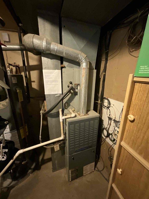 Completed comprehensive full system HVAC estimate for residential property, evaluating existing outdoor air conditioning condenser unit positioned on concrete pad adjacent to vinyl-sided structure and indoor furnace system located in utility room. Assessed gray condenser unit with cylindrical top fan grille showing typical outdoor weathering, verified unit placement on concrete base with surrounding landscape considerations, and documented electrical connections and manufacturer specifications. Evaluated indoor furnace equipment including ductwork configuration, flexible metallic duct routing, associated piping systems, and electrical connections in confined utility space. Provided equipment replacement recommendations and upgrade options based on current system condition, operational status, and homeowner comfort requirements for properly sized HVAC solution.