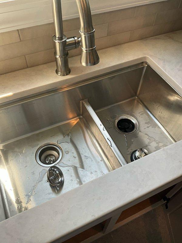Completed installation of client-provided kitchen faucet and garbage disposal unit in double-basin undermount stainless steel sink. Supplied and installed new basket strainer assembly and two P-traps to ensure proper drainage configuration. All plumbing connections tested and verified leak-free, with one-year labor warranty provided on installation work performed.