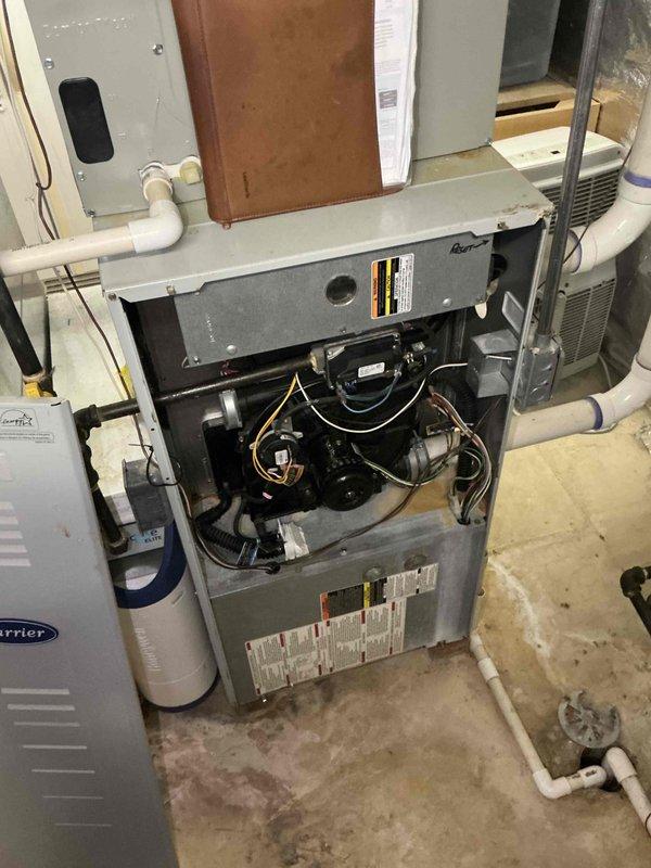 Conducted on-site evaluation of existing HVAC system for replacement estimate. Inspected 25+ year old furnace and air handler unit showing significant age-related wear. Documented current equipment configuration including gray metal furnace with accessible internal components, blower motor assembly, and wiring harnesses. Assessed Carrier-branded air conditioning unit and associated ductwork system. Photographed existing PVC condensate piping, copper refrigerant lines, and metal ductwork connections throughout basement installation. Evaluated overall system layout and clearances for potential replacement equipment. Provided comprehensive assessment of aging equipment condition to support replacement recommendations.