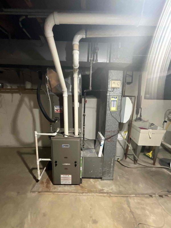 Completed full system estimate for residential HVAC replacement including outdoor air conditioning unit and indoor furnace with air handler. Documented existing equipment configuration showing outdoor condenser positioned on concrete pad with associated refrigerant lines, electrical disconnect, and PVC condensate drainage, as well as basement-installed furnace and air handler with existing venting system. Assessed complete system for replacement recommendations to ensure proper sizing and equipment selection for optimal home comfort and efficiency.
