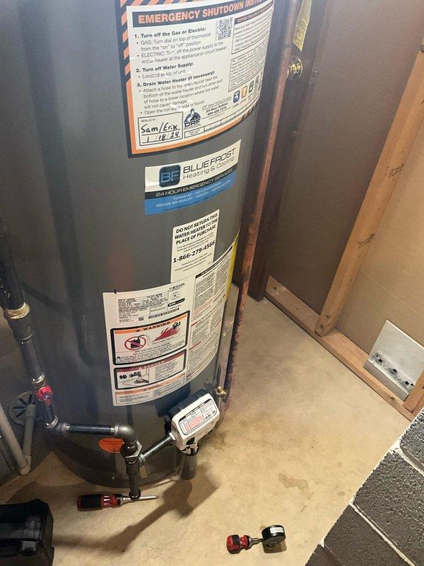 Completed comprehensive plumbing inspection of residential water supply system and water heating equipment. Documented water meter installation with Sensus digital meter, associated bypass valving, and copper supply piping showing normal age-related patina. Inspected and photographed residential water heater with proper emergency shutdown instructions posted, verified plumbing connections, shutoff valves operational, and leak detection device properly positioned at base of unit.