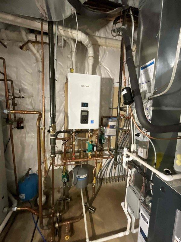 Completed full boiler replacement by installing a Navien NFB-175 unit with integrated manifold system and dehumidifier. Maintained existing zone control configuration while integrating new equipment with copper piping network, expansion tank, and PVC drainage systems. All connections, electrical components, and ventilation properly configured and tested for optimal system performance.