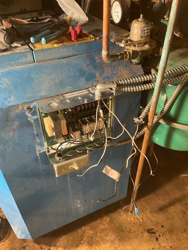 Responded to service call for boiler system with leaking piping and malfunctioning zone controller. Upon arrival, located active leak in copper piping connections within the mechanical room and assessed the existing zone control cabinet, which showed significant age-related deterioration with peeling paint and worn components. Retrieved necessary replacement parts from headquarters including new zone controller and plumbing fittings. Repaired leaking copper pipe connections using proper soldering techniques and installed replacement fittings where needed. Removed old zone controller from blue cabinet enclosure and installed new unit, reconnecting all electrical wiring, circuit breakers, and control mechanisms according to manufacturer specifications. Verified proper operation of ball valves, pressure gauges, and associated plumbing connections throughout the boiler system. Tested zone controller functionality to ensure proper communication with boiler and heating zones. System restored