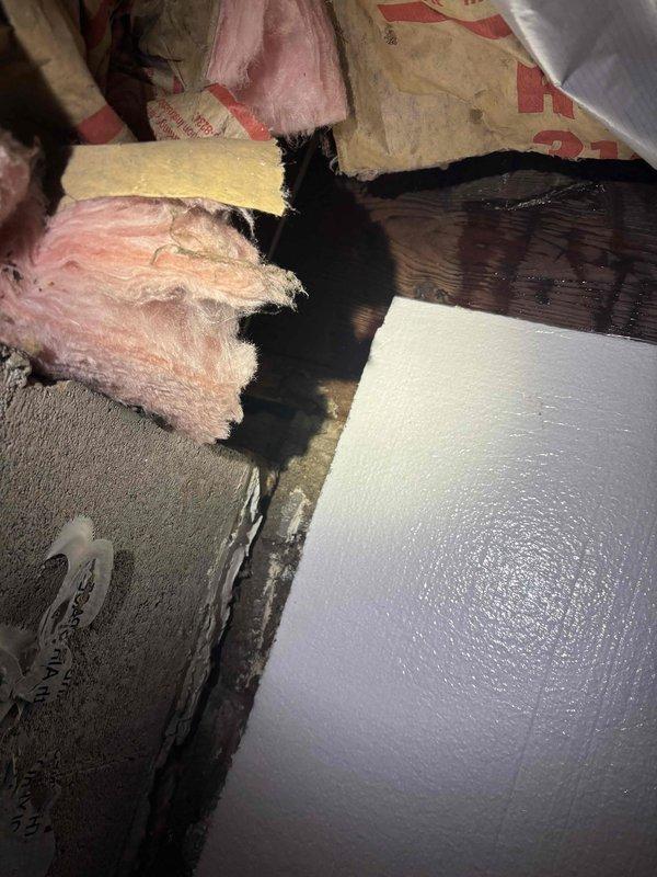 Responded to callback regarding moisture concerns following recent air conditioning installation. Upon inspection, discovered significant water damage and black staining on structural wooden beams and insulation in attic space near exterior wall where refrigerant lines were installed. Evidence indicates moisture intrusion affecting fiberglass insulation, foam board, and framing members. Documented extensive damage with photographs showing saturated materials and discoloration patterns. Investigation revealed the moisture issue appears related to condensation from improperly insulated refrigerant lines or drainage problems from the new AC system installation, causing water to migrate through the wall cavity into both the interior living space and basement area.