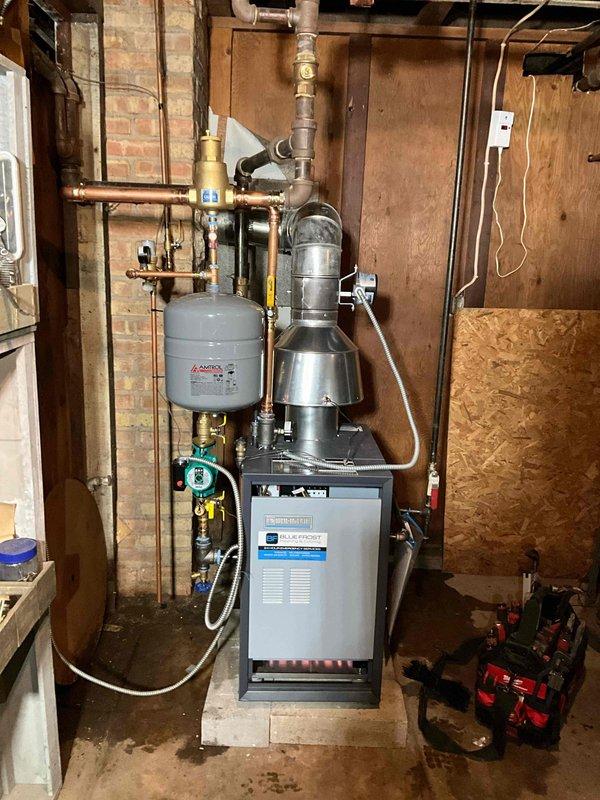 Completed full replacement of residential boiler system with new Weil-McLain CGA-5 unit. Removed existing boiler and installed new unit on concrete pad in basement utility area. Connected all copper supply and return piping with brass fittings and valves throughout the system. Mounted expansion tank to wall with proper copper piping connections. Installed circulation pump with necessary valves and controls for proper system operation. Connected pressure relief valve and all required safety components per manufacturer specifications. Installed exhaust vent piping extending from top of unit. Tested all connections for leaks, verified proper operation of circulation pump, and confirmed system pressurization. System commissioned and operational.