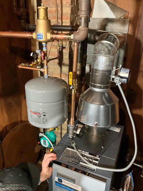 Completed full replacement of residential boiler system with new Weil-McLain CGA-5 unit. Removed existing boiler and installed new unit on concrete pad in basement utility area. Connected all copper supply and return piping with brass fittings and valves throughout the system. Mounted expansion tank to wall with proper copper piping connections. Installed circulation pump with necessary valves and controls for proper system operation. Connected pressure relief valve and all required safety components per manufacturer specifications. Installed exhaust vent piping extending from top of unit. Tested all connections for leaks, verified proper operation of circulation pump, and confirmed system pressurization. System commissioned and operational.