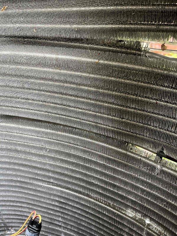 Completed comprehensive BFMA tune-up service on one-year-old HVAC system, including air conditioning system inspection and filter replacement. Inspected evaporator coil assembly and observed dust and debris accumulation on aluminum fins with some discoloration present; verified coil structural integrity remains intact with no damage to fin spacing or copper refrigerant lines. Replaced air filter, confirmed proper system operation, and documented equipment condition with photos showing coil surfaces and refrigerant line connections with brass fittings in satisfactory working order.