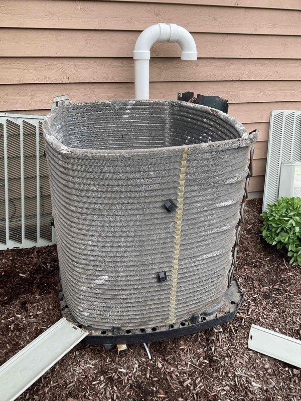 # BFMA AC Tune-Up Completed

Performed preventive maintenance tune-up on outdoor condensing unit per BFMA service agreement. Upon arrival, observed cylindrical condenser coil with visible wear and damaged outer casing sections, particularly at top where internal structure was exposed. Unit showed signs of age and extended outdoor exposure with missing portions of exterior housing and black mounting brackets visible on surface.

During inspection, identified significant frost and ice accumulation covering entire outer surface of aluminum fin coil assembly. Thick crystalline layer of ice was present uniformly across horizontal fins, indicating potential refrigerant flow restriction or low charge condition. Ice buildup was extensive enough to obscure underlying metal structure of coil surfaces.

Completed standard BFMA tune-up protocol including visual inspection of all accessible components, condenser coil assessment, and system evaluation. Unit positioned on concrete pad with proper dra
