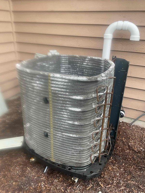 # BFMA AC Tune-Up Completed

Performed preventive maintenance tune-up on outdoor condensing unit per BFMA service agreement. Upon arrival, observed cylindrical condenser coil with visible wear and damaged outer casing sections, particularly at top where internal structure was exposed. Unit showed signs of age and extended outdoor exposure with missing portions of exterior housing and black mounting brackets visible on surface.

During inspection, identified significant frost and ice accumulation covering entire outer surface of aluminum fin coil assembly. Thick crystalline layer of ice was present uniformly across horizontal fins, indicating potential refrigerant flow restriction or low charge condition. Ice buildup was extensive enough to obscure underlying metal structure of coil surfaces.

Completed standard BFMA tune-up protocol including visual inspection of all accessible components, condenser coil assessment, and system evaluation. Unit positioned on concrete pad with proper dra