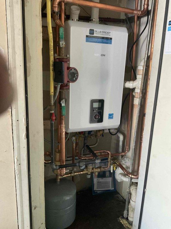 Completed installation of Navien combi boiler system with comprehensive copper piping network, including integration of reused circulator pump and existing PVC venting. The 20-hour installation featured professional plumbing connections with multiple isolation valves, pressure relief components, and dual expansion tanks for proper system pressurization and thermal expansion control. All connections were tested and verified operational with digital control panel programmed for optimal heating and domestic hot water performance.