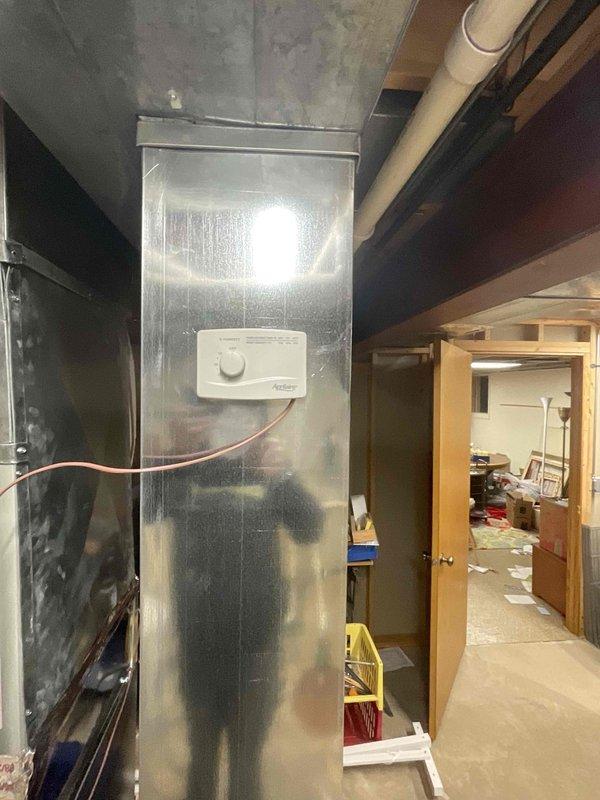 # HVAC Install - Furnace

Completed installation of Lennox furnace system in basement mechanical room, replacing existing heating equipment. Installed new beige Lennox furnace unit with proper vertical mounting and secured all manufacturer specification labels and safety documentation to unit front panel. Connected white PVC venting system along left side of unit with both vertical and horizontal runs to ensure proper exhaust ventilation. Fabricated and installed silver metal supply plenum at furnace top, connecting to existing ductwork distribution system. Installed sheet metal return air duct on right side of furnace with white access panel for filter maintenance and system inspection. Routed electrical connections to furnace and mounted white control unit to ductwork for system operation. All ductwork connections sealed and secured to prevent air leakage. Verified proper clearances around unit for service access and safety compliance. System tested and confirmed operational.