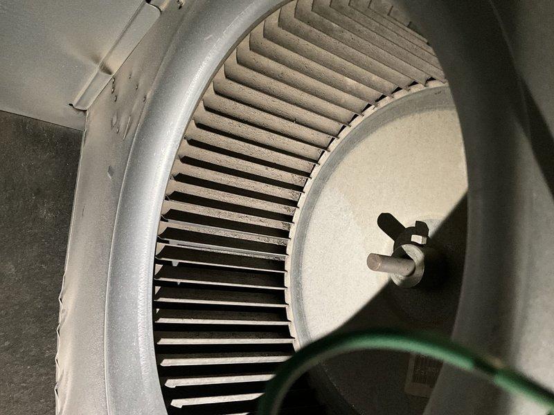 Responded to after-hours heating system failure on 20+ year old residential HVAC unit. Upon arrival, inspected Honeywell Chronotherm IV Plus programmable thermostat showing hold mode at 69°F and conducted visual assessment of blower assembly. Documented significant dust accumulation on squirrel cage blower wheel blades and housing, which can restrict airflow and cause system performance issues. Photographed blower wheel assembly showing dusty metal blades and central hub with motor coupling, as well as thermostat display for diagnostic reference.