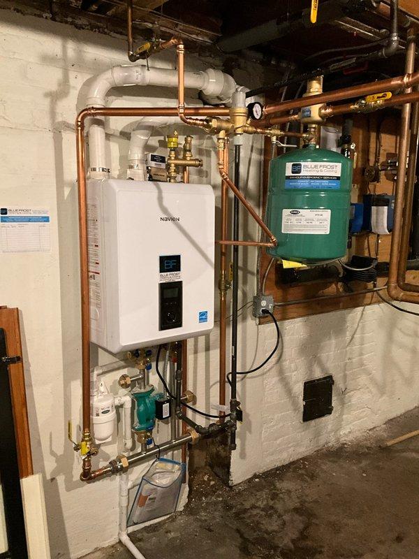 # HVAC Install - Boiler

## Work Performed

Completed full boiler replacement with installation of Navien NHB-150 tankless boiler system. Removed existing boiler unit and installed new wall-mounted tankless boiler on concrete block wall in basement mechanical room. 

Installed complete copper piping network with brass fittings and shut-off valves to connect tankless boiler to existing indirect water tank. Configured system for two-zone heating operation as specified. Mounted expansion tank on wall adjacent to main unit and integrated into system with proper connections.

Installed Navien manifold kit to facilitate multi-zone distribution. Added circulation pump at floor level to ensure proper flow throughout system. Ran PVC venting pipes from unit through ceiling for exhaust and combustion air intake per manufacturer specifications.

Installed condensate neutralizer to treat acidic condensate discharge from high-efficiency boiler operation, ensuring compliance with local codes. Integra