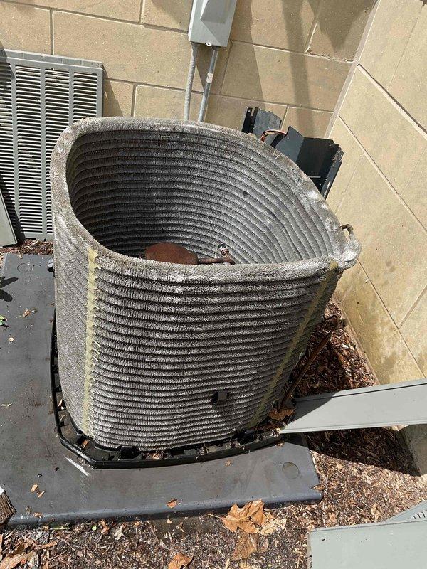 Completed BFMA tune-up on residential AC condenser unit at rental property. Inspected compressor, motor assembly, and cylindrical condenser coil which showed accumulation of debris, leaves, and organic matter throughout exterior fins and base area. Documented equipment condition with photos showing aging unit with visible wear, corroded components, and electrical connections requiring monitoring for future service needs.