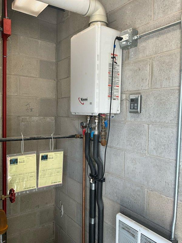 Responded to no hot water complaint at commercial facility. Upon inspection, found Rinnai tankless water heater installed and operational in mechanical room. Verified unit power supply, gas connections, and exhaust venting were properly configured. Tested hot water flow at multiple fixtures throughout building and confirmed adequate hot water delivery to all locations except reported shower head. Traced plumbing distribution system and determined issue was isolated to individual fixture rather than water heater malfunction. Tankless unit displaying normal operating parameters with no error codes present. Recommended client contact plumbing division to inspect shower valve cartridge and fixture-specific supply lines for potential blockage or mechanical failure at point of use.