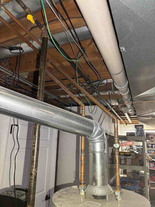 Responded to after hours service call for water heater system inspection. Upon arrival, documented existing basement mechanical room configuration including water heater installation with expansion tank, copper supply lines, and associated plumbing connections. Water softener system with digital display panel observed operating adjacent to water heater unit. Verified proper clearances around equipment and documented current installation conditions including exposed ceiling utilities, HVAC ductwork, electrical conduits, and plumbing distribution lines throughout mechanical space. All equipment photographed for service records showing white cylindrical pressure tank, brass fittings, copper piping connections, and water treatment system. No immediate repairs required at time of inspection.
