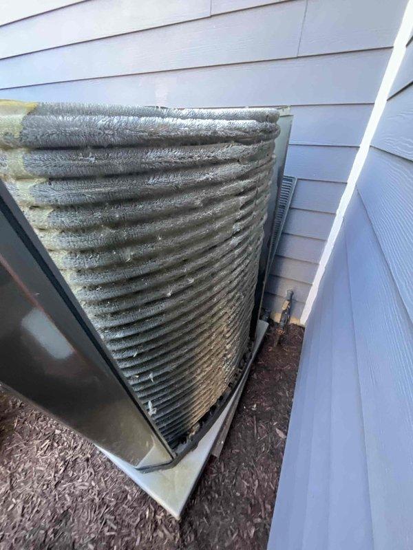Completed comprehensive HVAC maintenance and tune-up inspection on outdoor heat pump/air conditioning condenser unit. Upon arrival, found extensive dirt, debris, and dust accumulation on cylindrical finned coil structure requiring thorough cleaning to restore optimal heat transfer efficiency. Performed electrical diagnostics using clamp meter, recording amperage readings at 00.2A to verify proper system operation and component function. Cleaned condenser coils, inspected all electrical connections and components including capacitors, and verified system performance meets manufacturer specifications.