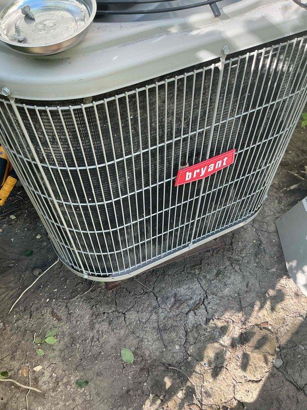Completed comprehensive BFMA tune-up service on 9-year-old Bryant air conditioning system. Upon arrival, discovered outdoor condenser unit in severely deteriorated condition with top cover completely missing, exposing internal components including fan motor assembly. Noted significant weathering damage with compromised housing, jagged edges around top opening, deteriorating insulation material, and dark staining throughout unit indicating extensive rust and possible mold accumulation. Documented damaged protective grille and exposed mechanical components. Unit positioned on weathered, cracked concrete pad with vegetation growth nearby. Performed standard AC tune-up procedures including system inspection, operational assessment, and photographic documentation of equipment condition. Advised customer of critical safety concerns and structural damage requiring immediate attention for proper system function and efficiency.