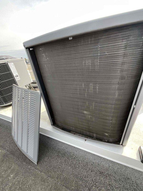 Completed comprehensive BFMA tune-up on rooftop-mounted air conditioning unit aged 4+ years. Performed full system inspection with access panel removal to evaluate condenser coil condition, noting dust and debris accumulation on horizontal fins typical of outdoor installation. Conducted standard maintenance protocol including visual assessment of internal components, coil examination, and overall equipment operational review to ensure proper system performance for the cooling season.
