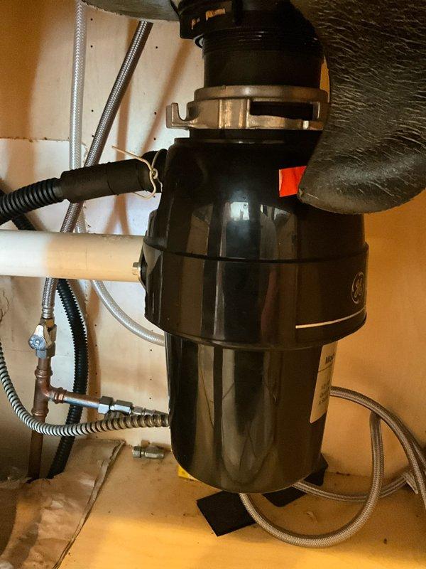 Responded to service call for clogged kitchen sink with reported leaking beneath cabinet. Upon arrival, inspected under-sink plumbing assembly and garbage disposal unit. Identified blockage in drain line causing backup and slow drainage. Cleared obstruction from disposal and drain system using appropriate methods. Tested disposal operation and verified reset button functionality. Inspected all PVC drain connections, P-trap assembly, and supply lines for source of reported leak. Tightened fittings as needed and confirmed proper drainage flow. Verified all connections were secure with no active leaks present. System restored to full working order with proper drainage confirmed.