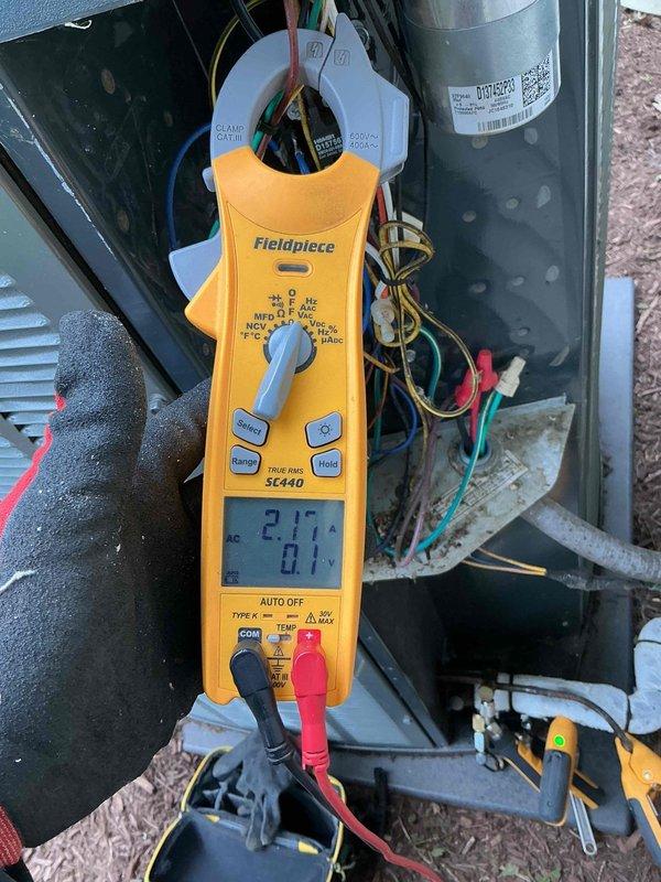 Completed comprehensive BFMA air conditioning tune-up and preventive maintenance service on outdoor condenser unit. Upon arrival, performed visual inspection revealing significant dirt accumulation and debris lodged between coil fins, indicating extended service interval and environmental exposure. Cleaned condenser coils to remove deteriorated insulation material and buildup affecting heat transfer efficiency. Performed electrical diagnostics using clamp meter to verify compressor amperage draw at 21.6 amps, confirming unit operating within normal parameters. Inspected all electrical connections, wiring, and mounting hardware for proper operation. Unit tested and left in operational condition with improved airflow through coils for optimal cooling performance.