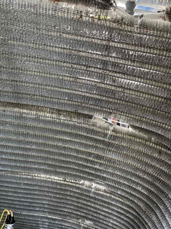 Completed comprehensive BFMA tune-up service on residential HVAC system with equipment age of 1+ years. Performed thorough inspection of condenser unit, including examination of evaporator coil and condenser coil fins which showed moderate accumulation of dirt, dust, and debris. Measured system parameters and documented equipment condition with photographic evidence showing cylindrical heat exchanger coil assembly and compressor unit requiring attention due to contamination between fin rows.