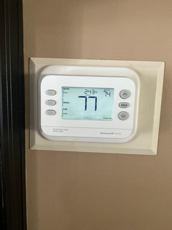 Responded to no cooling call at residential property. Upon arrival, found Honeywell Home thermostat displaying 77°F actual temperature with cooling mode active and setpoint at 74°F, but system not operating. Removed thermostat cover and inspected wiring connections at terminal block. Verified proper wire terminations at R, C, Y, and G terminals. Identified thermostat communication or wiring issue preventing cooling call signal from reaching outdoor unit. Accessed crawlspace after 3PM as requested due to restricted access in older home. Corrected wiring connections and restored proper thermostat operation. System now cooling properly with thermostat successfully calling for cooling and maintaining setpoint. Unit tested and left in operational condition.