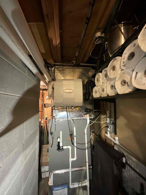Completed installation of Lennox EL18KCV-048-230 air conditioning unit with matching CK40CT-48C-71 evaporator coil. System was installed in basement utility area with outdoor condensing unit positioned on metal platform with proper refrigerant line connections, filter-drier, and service valves. Thermostat was reinstalled and system was tested for proper operation, with 10-year parts and labor warranty coverage activated.