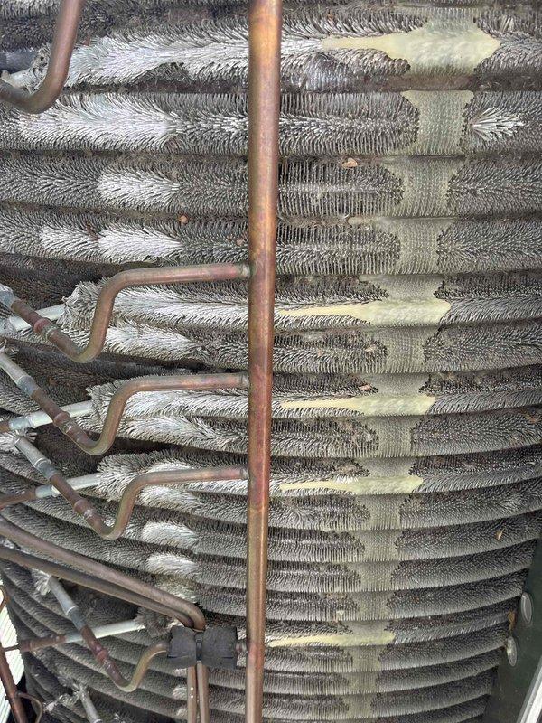 Completed comprehensive BFMA tune-up on residential air conditioning system. Upon inspection, discovered significant frost and ice accumulation on evaporator coils with heavy buildup obscuring aluminum fins, indicating potential airflow restriction or refrigerant issue. Documented condition of copper refrigerant lines showing normal oxidation patina, and noted dust and particulate matter accumulation on air filter and coil surfaces that required attention for optimal system performance.