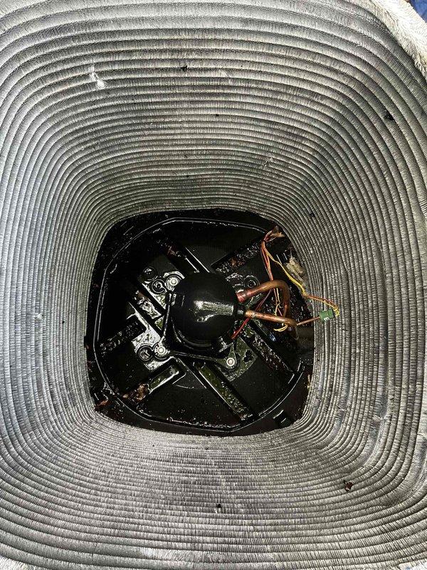 Completed comprehensive BFMA tune-up on 2-year-old outdoor HVAC condenser unit. Removed accumulated leaves and organic debris from interior components, motor housing, and base plate that had collected through top grille. Inspected condenser coils, copper refrigerant lines, electrical connections, and motor assembly; verified all components in proper working condition with fins maintaining correct spacing and alignment.