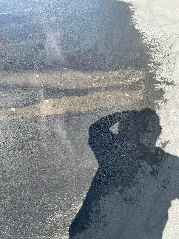 Responded to callback for driveway staining concerns following initial service visit. Upon arrival, assessed asphalt driveway surface showing darker sealant patches and irregular color variations across the pavement. Deployed power washing equipment to address staining and surface discoloration as requested. Treated affected areas where sealant material had created uneven appearance and glossy patches contrasting with weathered concrete sections. Completed surface cleaning procedures and documented final condition showing uniform dark gray asphalt surface with typical tire marks and scuff patterns consistent with normal driveway use.