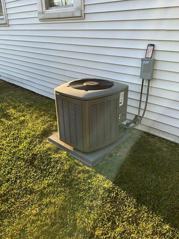 Completed comprehensive BFMA tune-up on residential air conditioning system, arriving after 5 PM per customer's work schedule. Performed standard maintenance protocol including inspection of outdoor condenser unit, which revealed significant damage with top protective grille and cover completely missing, exposing interior coil structure. Noted condenser coil showing weathered appearance with frayed edges where protective casing has deteriorated. Inspected refrigerant lines, electrical connections, and service valves with yellow and red components, confirming all connections secure. Verified electrical disconnect box mounted on exterior wall functioning properly with conduit connections intact. Documented unit condition with photographs for service records, noting equipment positioned on concrete pad with adequate clearance from structure.