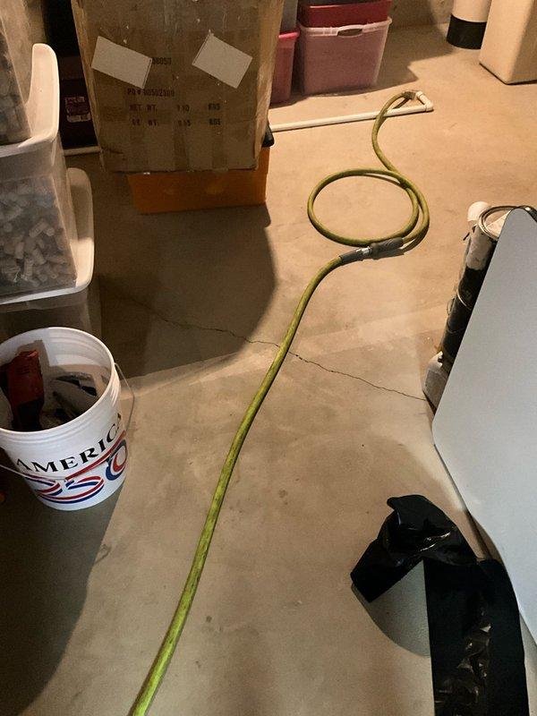 Completed isolation and drainage of existing tanked water heater in basement utility area. Shut off water supply to unit and connected drainage hose to drain valve at base of tank. Carefully routed garden hose across concrete floor to appropriate drainage point, taking precautions to avoid contact with white carpeting in adjacent areas. Successfully drained water heater tank completely, monitoring discharge throughout process. Verified all connections were secure during drainage operation. Protected surrounding area and maintained clean work environment throughout service, with particular attention to preventing water damage to flooring and stored items in basement space.