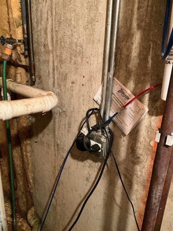 Completed pre-move-in plumbing inspection of residential property with focus on basement utility areas. Evaluated condition of water supply lines, shut-off valves, and drainage systems, noting visible moisture intrusion on concrete foundation walls with water staining patterns indicating potential seepage issues. Documented existing plumbing infrastructure including copper supply lines showing age-related patina, PVC drainage piping, and main water shut-off valve assembly with red ball valve for emergency isolation. Inspected sump pump system and related components for operational readiness. Photographed areas of concern including foundation wall moisture damage, plumbing connections, electrical outlet proximity to potential water exposure, and overall condition of mechanical systems for comprehensive assessment and future reference.