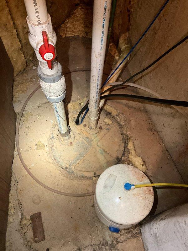 Completed pre-move-in plumbing inspection of residential property with focus on basement utility areas. Evaluated condition of water supply lines, shut-off valves, and drainage systems, noting visible moisture intrusion on concrete foundation walls with water staining patterns indicating potential seepage issues. Documented existing plumbing infrastructure including copper supply lines showing age-related patina, PVC drainage piping, and main water shut-off valve assembly with red ball valve for emergency isolation. Inspected sump pump system and related components for operational readiness. Photographed areas of concern including foundation wall moisture damage, plumbing connections, electrical outlet proximity to potential water exposure, and overall condition of mechanical systems for comprehensive assessment and future reference.