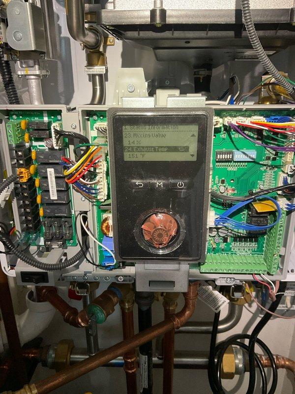 # Tankless Water Heater Diagnostic and Service

Responded to service call for tankless water heater malfunction on unit installed four months prior. Upon arrival, performed comprehensive diagnostic evaluation of the system including inspection of control board, digital display panel, and exhaust temperature readings. Control panel displayed exhaust temperature of 151°F during diagnostic testing.

Conducted thorough inspection of internal components including dual circuit boards, relay systems, capacitors, and integrated circuits. Verified all electrical connections, terminal blocks, and wiring harnesses for proper seating and continuity. Inspected copper supply and return lines, brass valves, and plumbing connections for proper flow and potential restrictions.

Examined exterior venting system including PVC exhaust and intake piping, ensuring proper termination, adequate clearances, and secure mounting to building structure. Verified vent pipe configuration meets manufacturer specifica