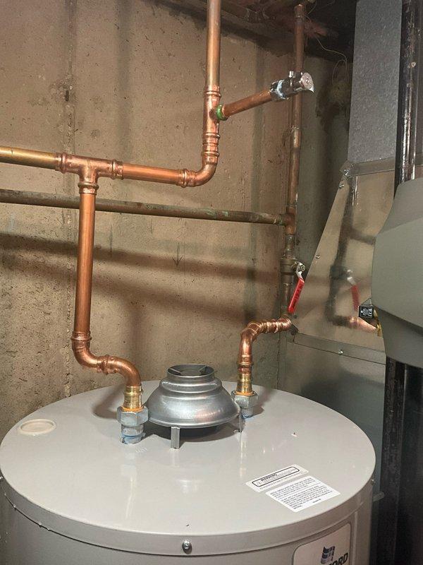 Completed full installation of Bradford White BFRG250T6N tanked water heater system in basement utility area. Professional copper piping connections were installed with proper fittings, valves, and solder joints for both hot and cold water lines, along with required PVC venting routed from the unit. Installation includes appropriate clearances for maintenance access and integration with existing HVAC system in mechanical room.