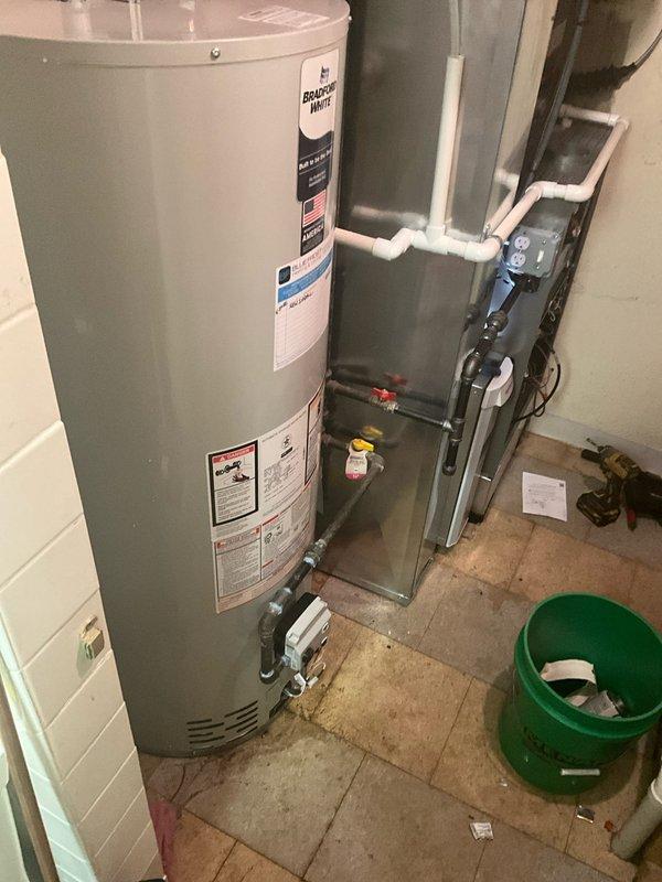 Completed full installation of Bradford White BFRG250T6N tanked water heater system in basement utility area. Professional copper piping connections were installed with proper fittings, valves, and solder joints for both hot and cold water lines, along with required PVC venting routed from the unit. Installation includes appropriate clearances for maintenance access and integration with existing HVAC system in mechanical room.